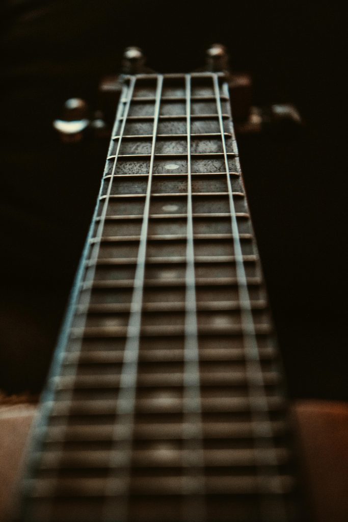 Artistic close-up of a guitar fretboard focusing on the strings and frets with a depth of field effect.