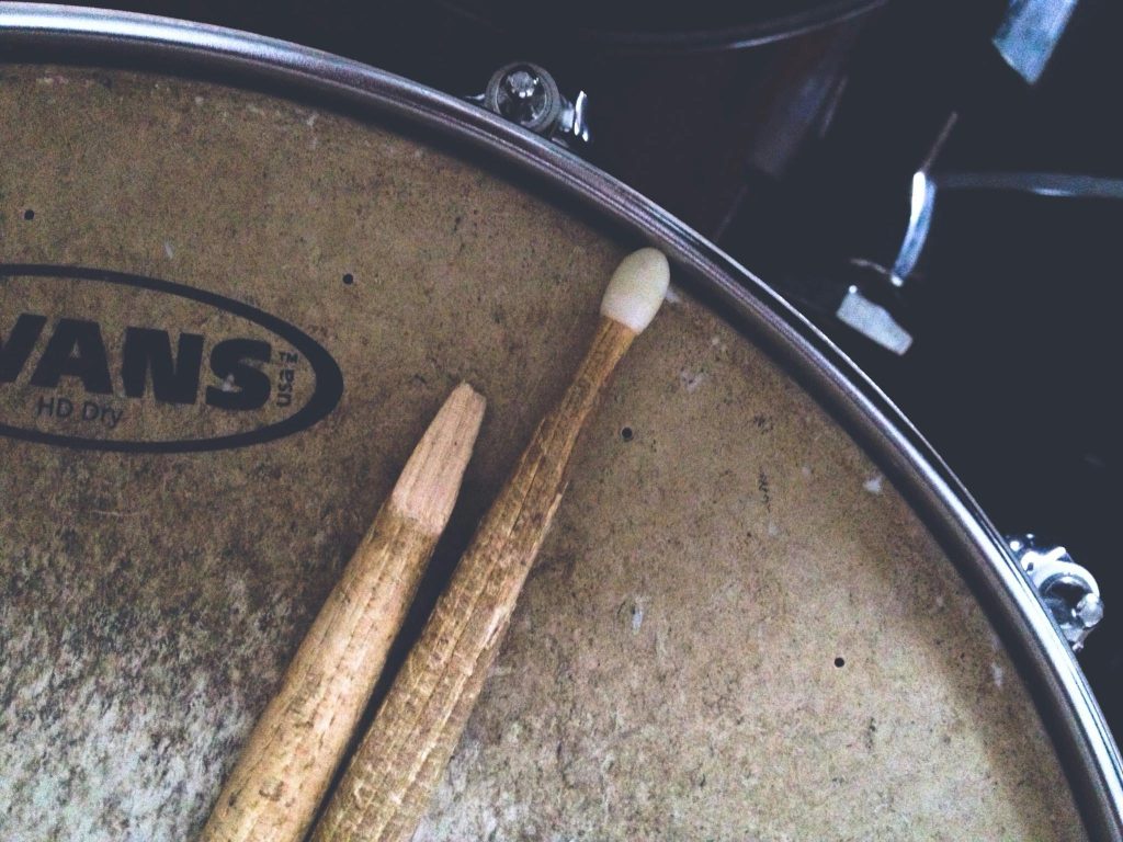 Detailed shot of a broken drumstick resting on a textured snare drum head. Musical vibes.